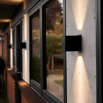 Black cube wall light beside a glass wall at night — Casa Norex