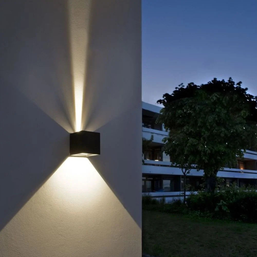 Light beams from a cube wall light against a dusk sky — Casa Norex