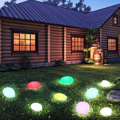 Color-changing stone lights in green, red and pink on a lawn by a log cabin | Casa Norex