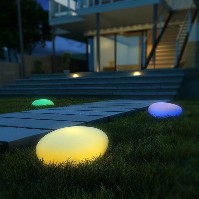 Yellow stone light glowing on a lawn beside patio steps — Casa Norex
