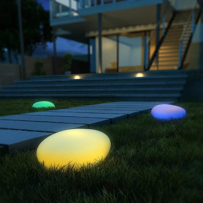 Yellow stone light glowing on a lawn beside patio steps — Casa Norex