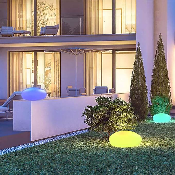 Glowing stone lights in blue, yellow and teal in front of a modern house — Casa Norex