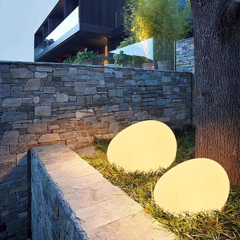 Warm glowing stone lights beside a stone retaining wall — Casa Norex