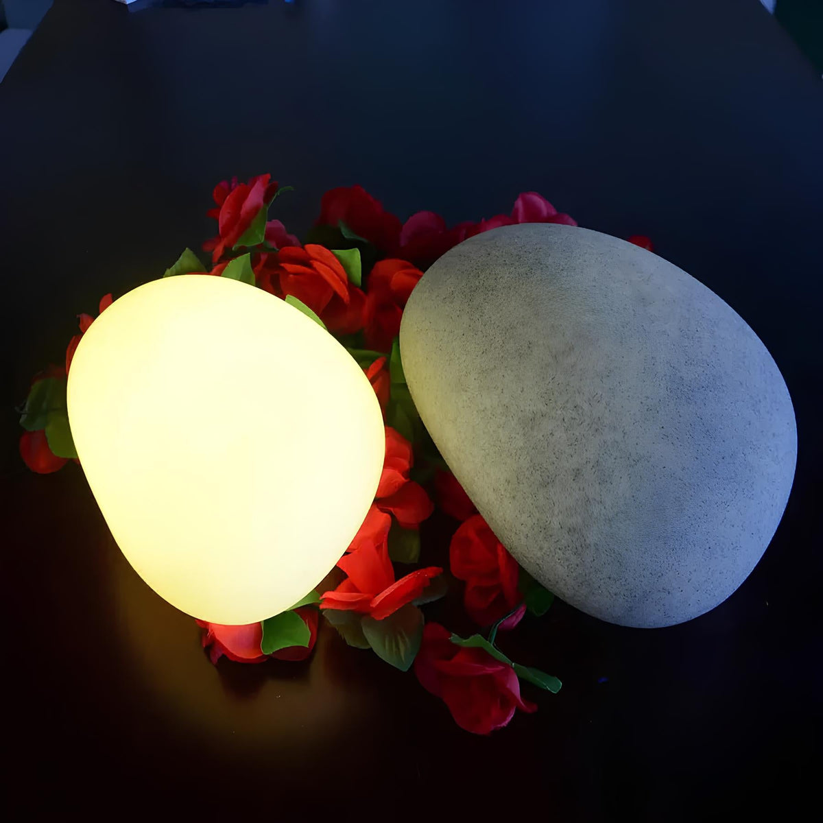 Warm glowing stone beside a grey stone surrounded by red roses — Casa Norex