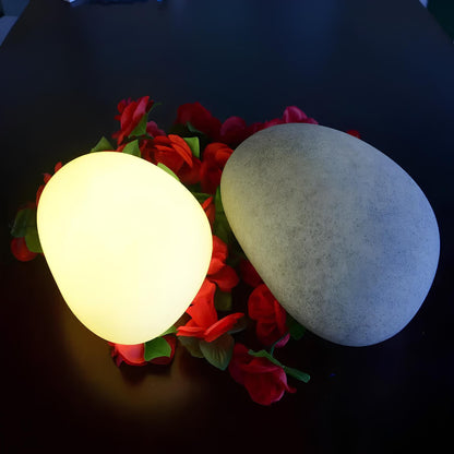 Warm glowing stone beside a grey stone surrounded by red roses — Casa Norex