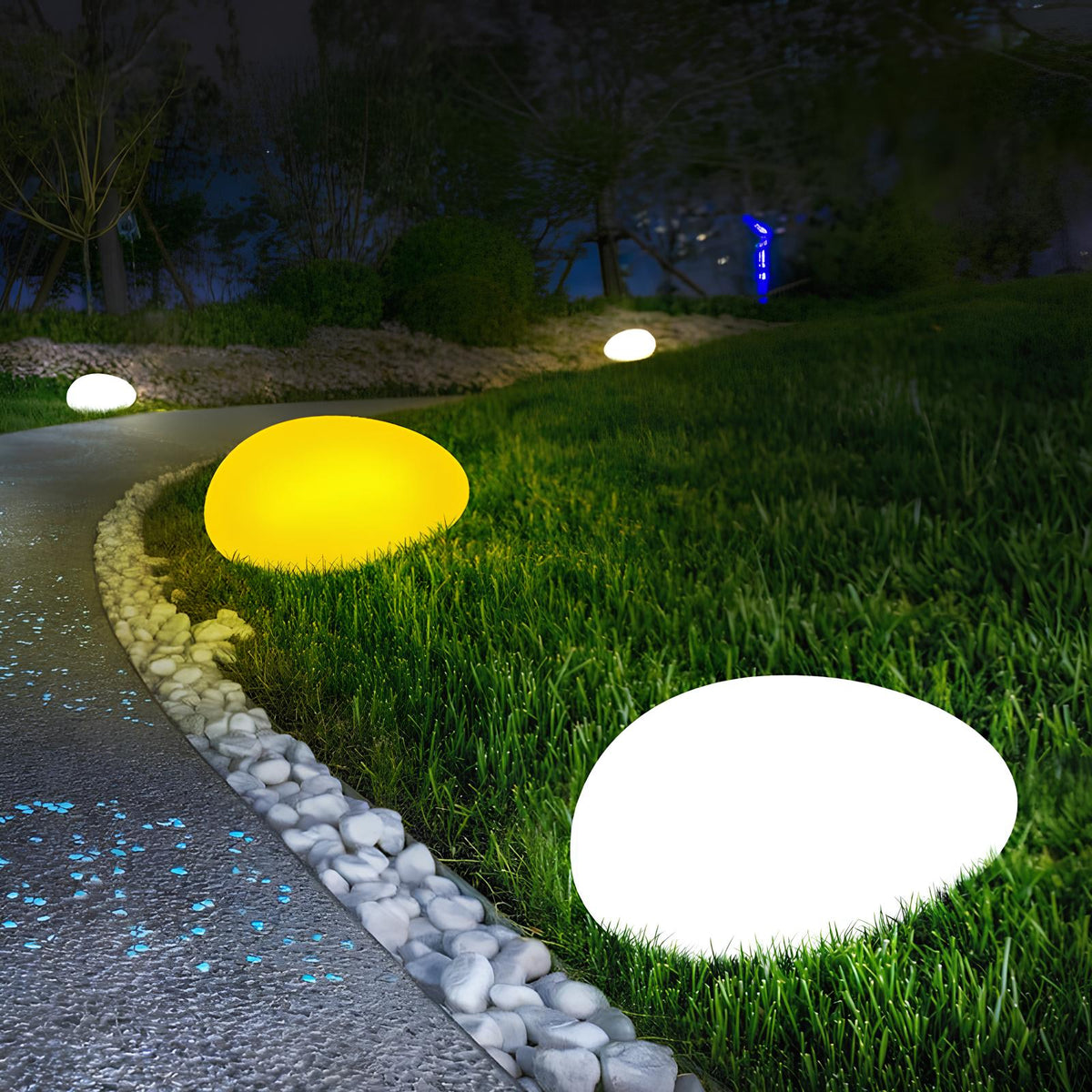 Yellow and white stone lights along a gravel garden path at night — Casa Norex