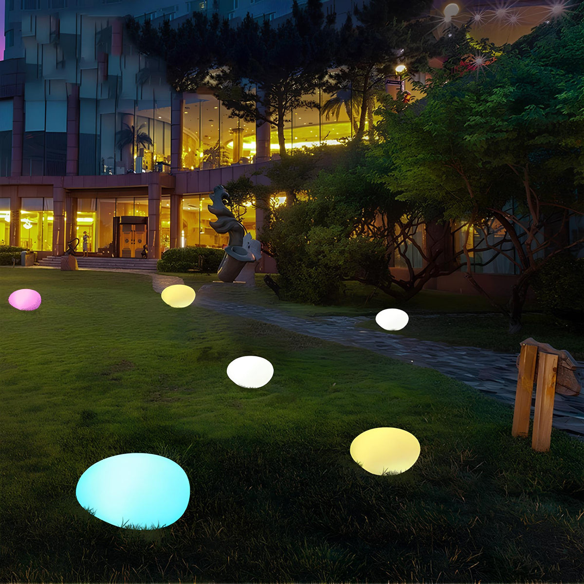 Multicolor stone lights in blue, yellow and pink on a lawn at night — Casa Norex