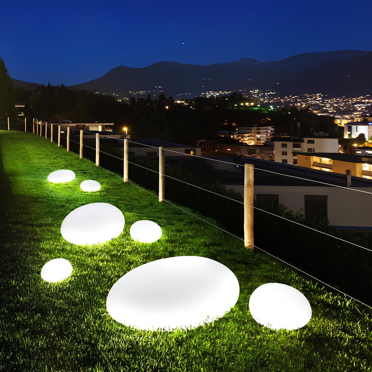 White stone lights on a lawn with a city view at night — Casa Norex
