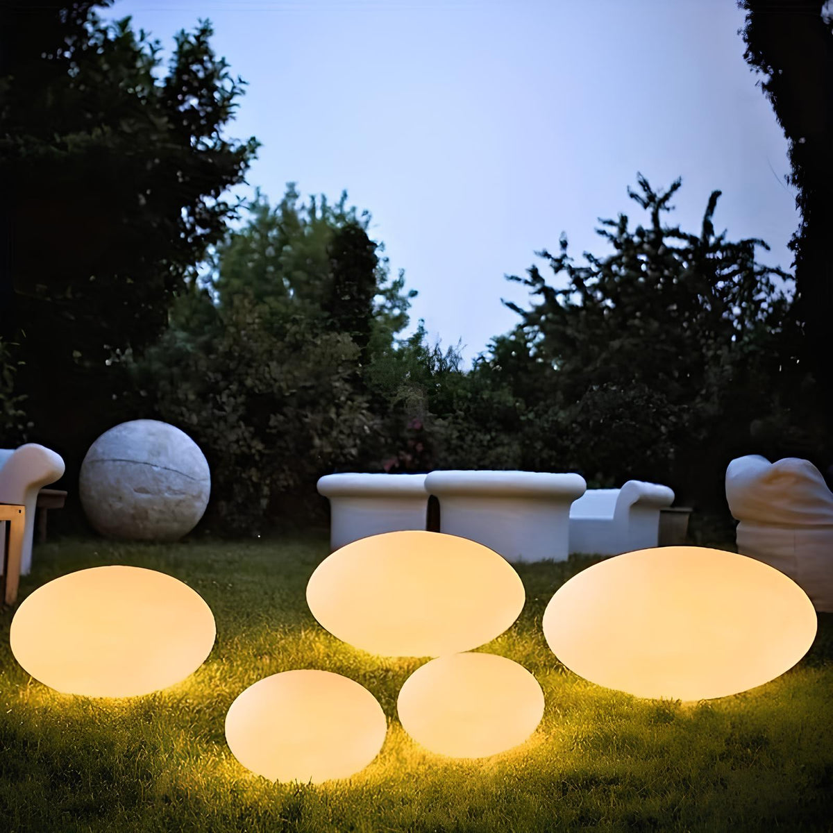 Warm white stone lights in a garden near outdoor seating at dusk — Casa Norex