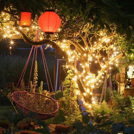 Solar string lights wrapped around a tree and swing in a garden at night | Casa Norex