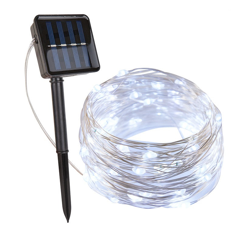 Cool white solar fairy lights coiled beside a solar panel on a ground stake | Casa Norex