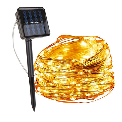 Warm white copper wire fairy lights coiled beside a solar panel on a stake — Casa Norex