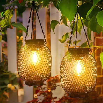 Two oval black mesh solar lanterns hanging and glowing warm gold | Casa Norex