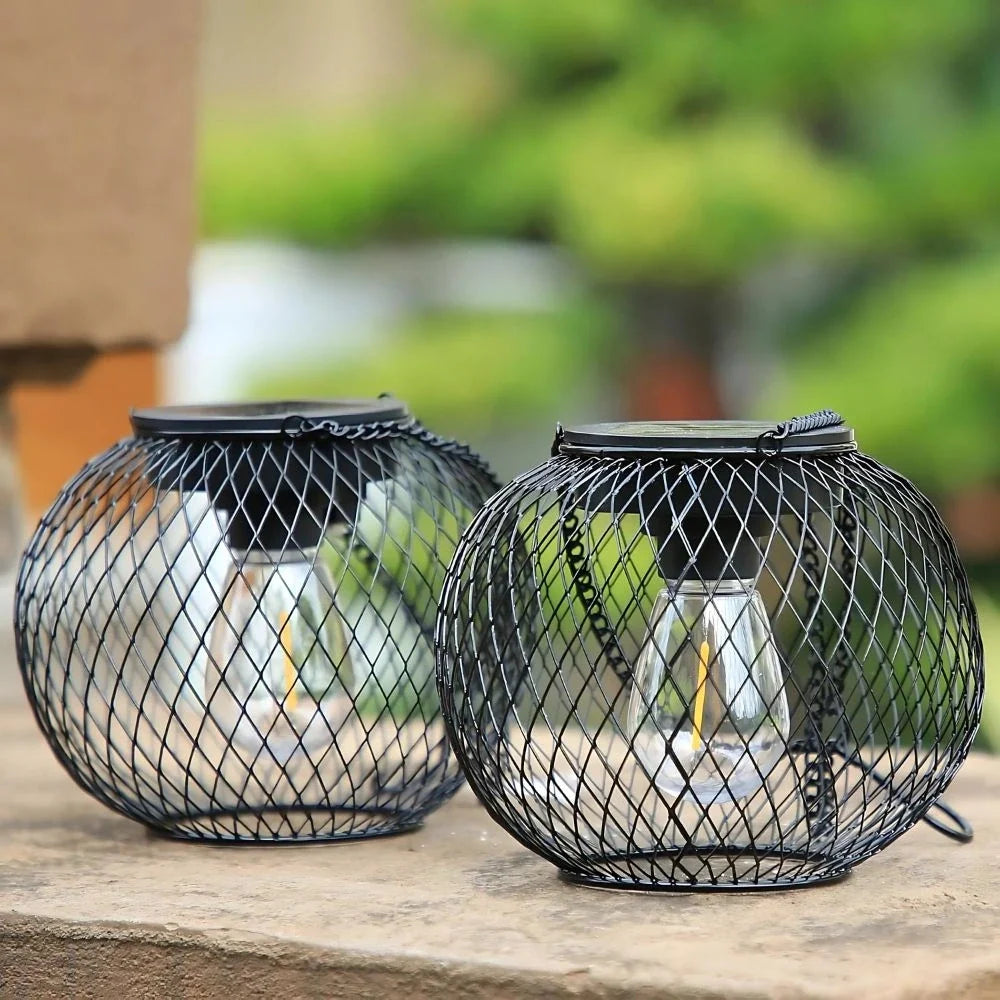 Round and oval black mesh lanterns resting side by side on a stone surface — Casa Norex