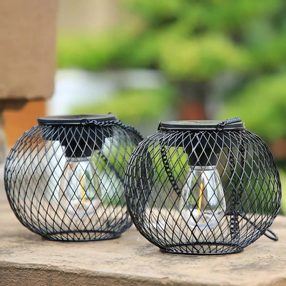 Round and oval black mesh lanterns resting side by side on a stone surface — Casa Norex