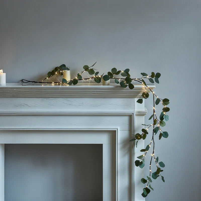 Garland with lights draped along a white fireplace mantel as a glowing ivy vine | Casa Norex