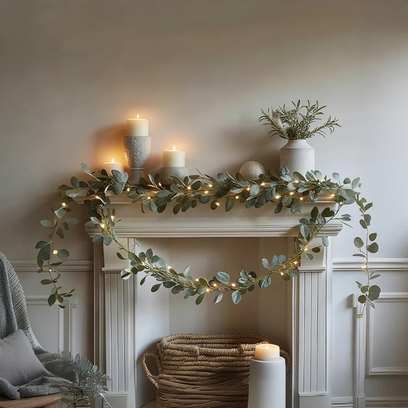 Eucalyptus garland lights on a mantel with candles and a small plant — Casa Norex