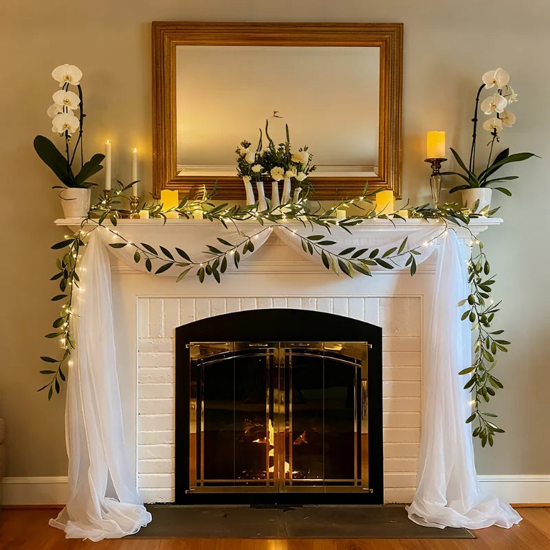 Olive leaf garland lights draped around a mirror over a white fireplace — Casa Norex