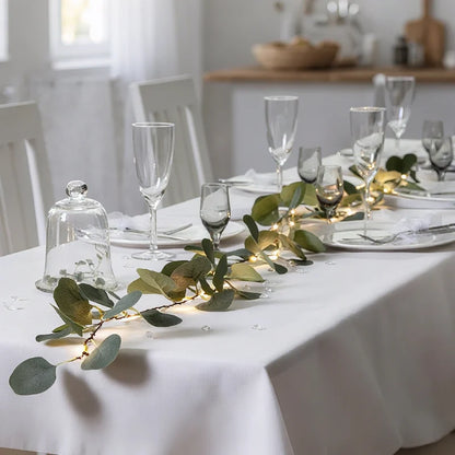 Eucalyptus garland lights along a white tablecloth with glasses — Casa Norex