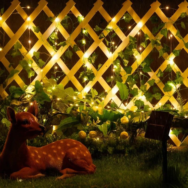 Garland lights on a lattice fence with a decorative deer in a garden — Casa Norex