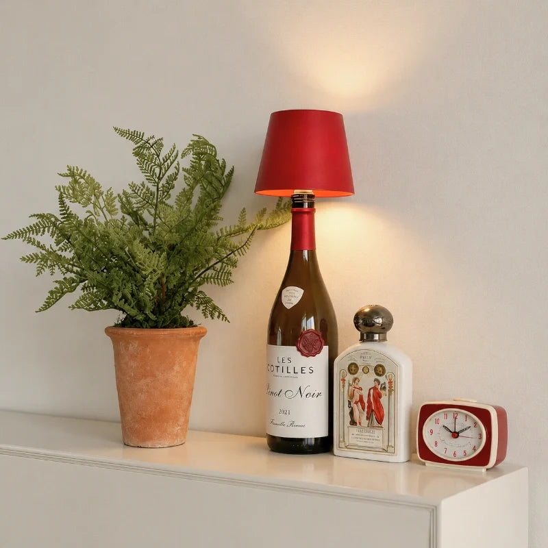 Red cordless bottle lamp on a wine bottle beside a fern on a white shelf | Casa Norex