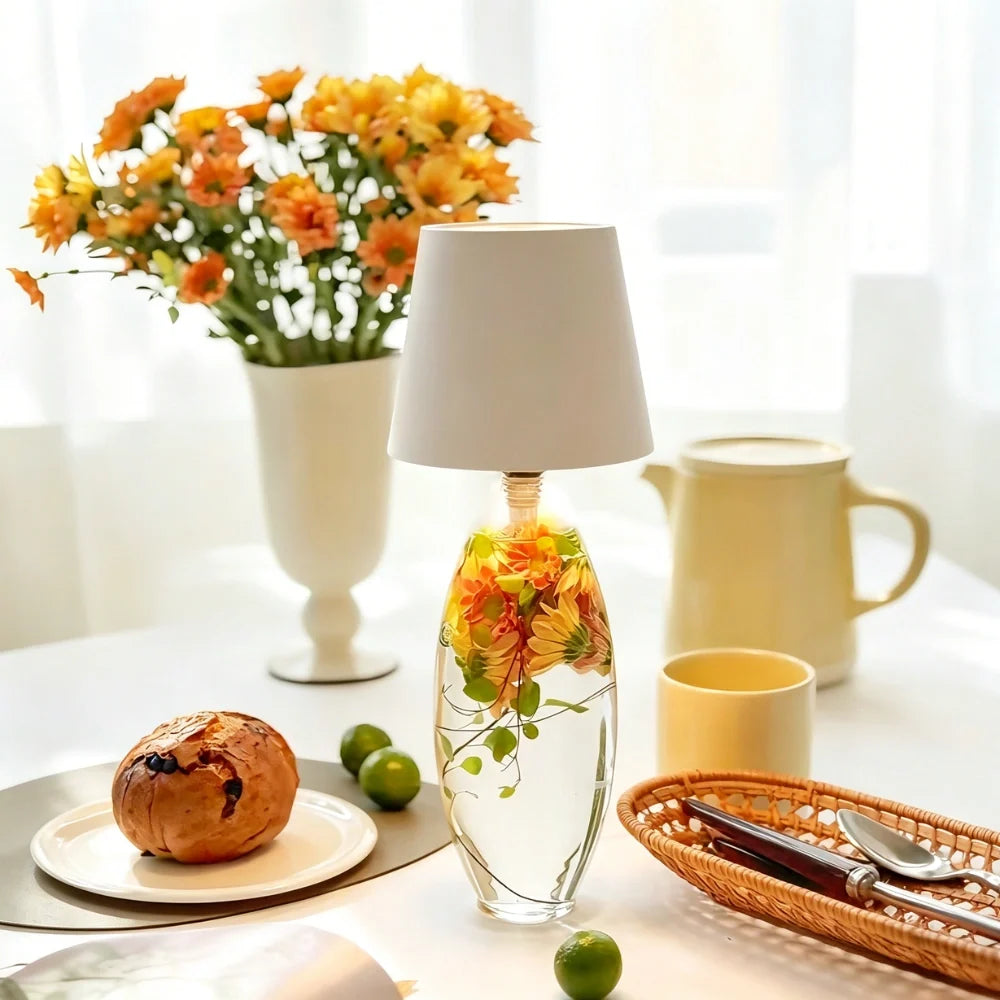 White cordless bottle lamp on a glass bottle among flowers and pastries | Casa Norex