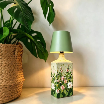Green cordless bottle lamp on a floral bottle beside a plant — Casa Norex