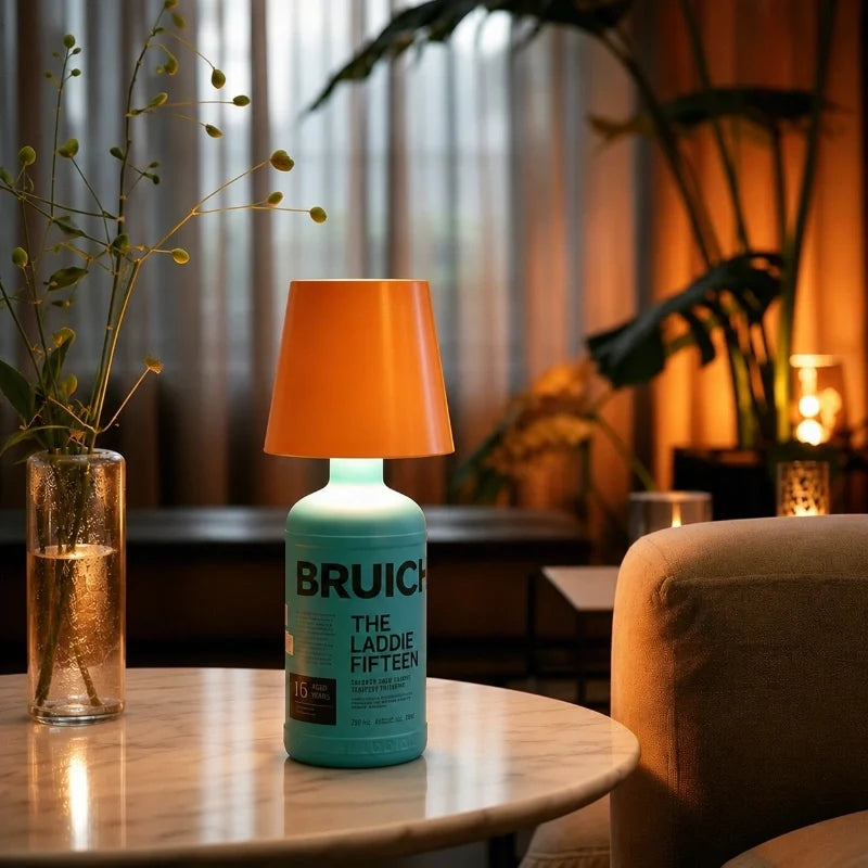 Orange cordless bottle lamp on a teal bottle beside a sofa — Casa Norex