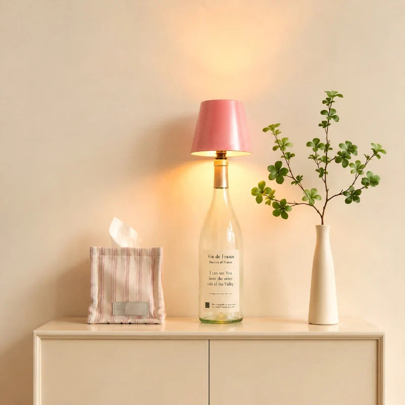 Pink cordless bottle lamp on a bottle beside a vase on a console — Casa Norex