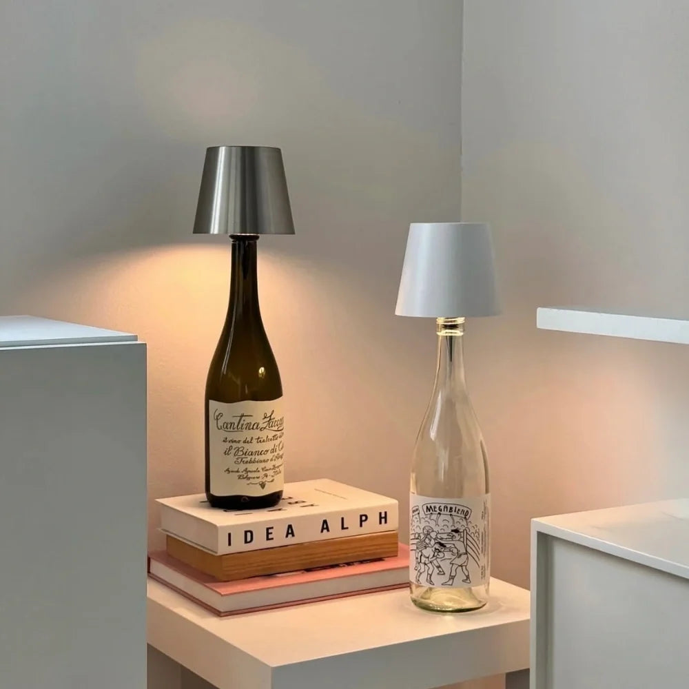 Two cordless bottle lamps on bottles stacked on books — Casa Norex