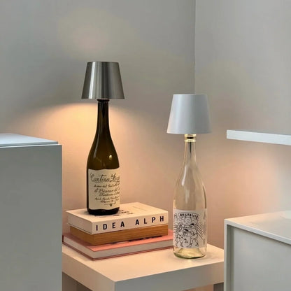 Two cordless bottle lamps on bottles stacked on books — Casa Norex