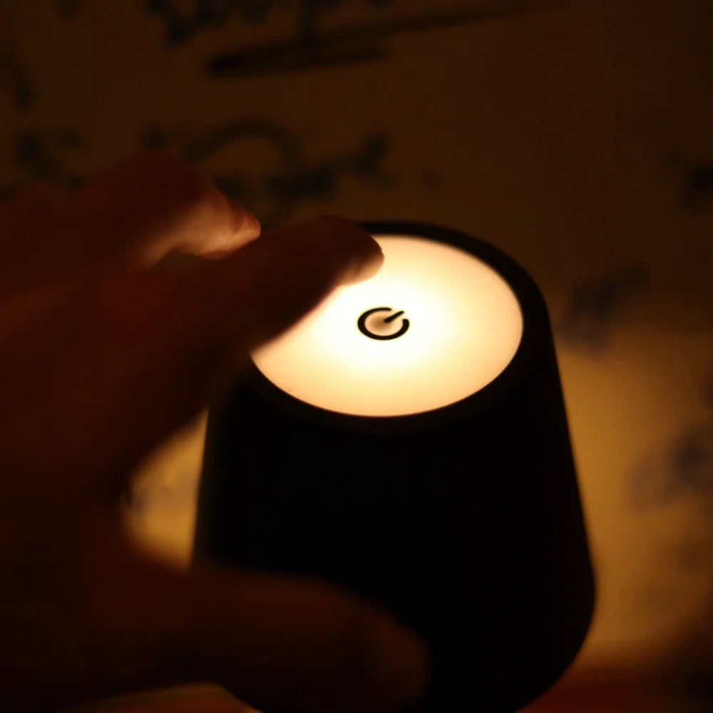 Hand touching a glowing black cordless bottle lamp — Casa Norex