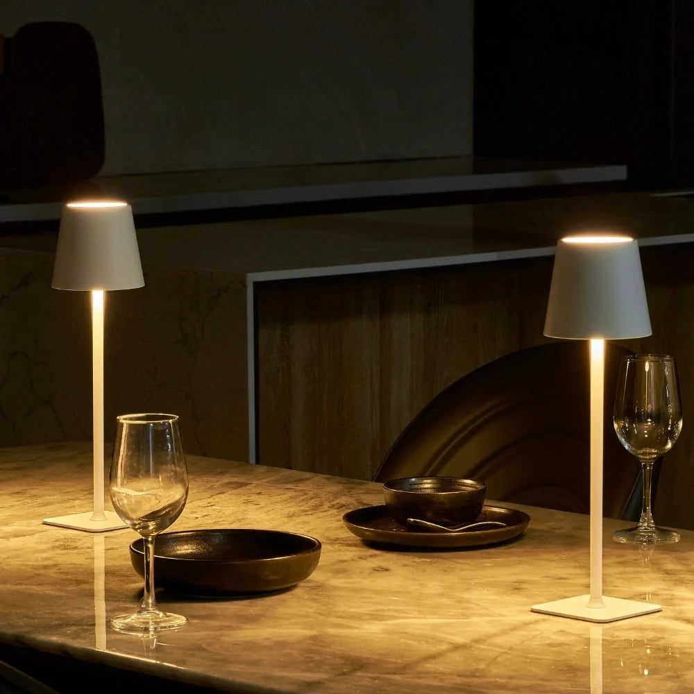 Two lit table lamps beside wine glasses at an evening table — Casa Norex