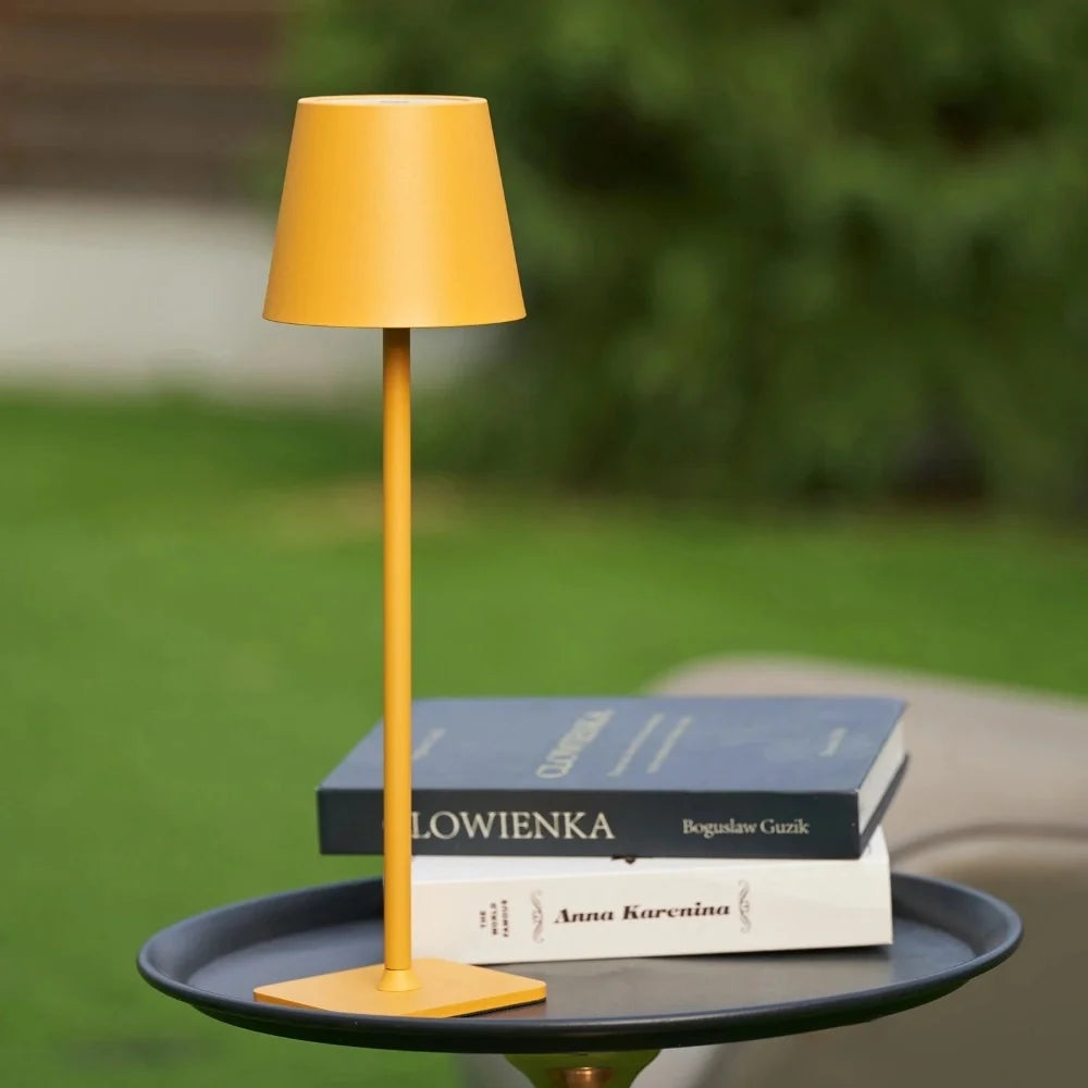 Matte yellow table lamp on a garden tray table with stacked books — Casa Norex